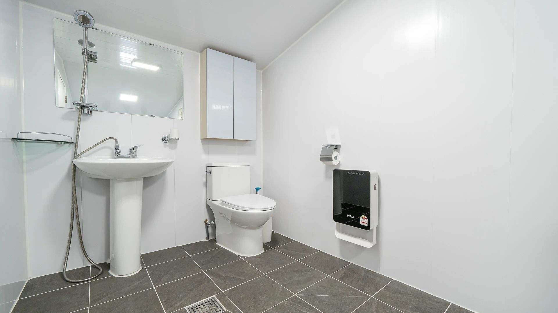 A modern bathroom with a white sink, toilet, and a glass shower enclosure.