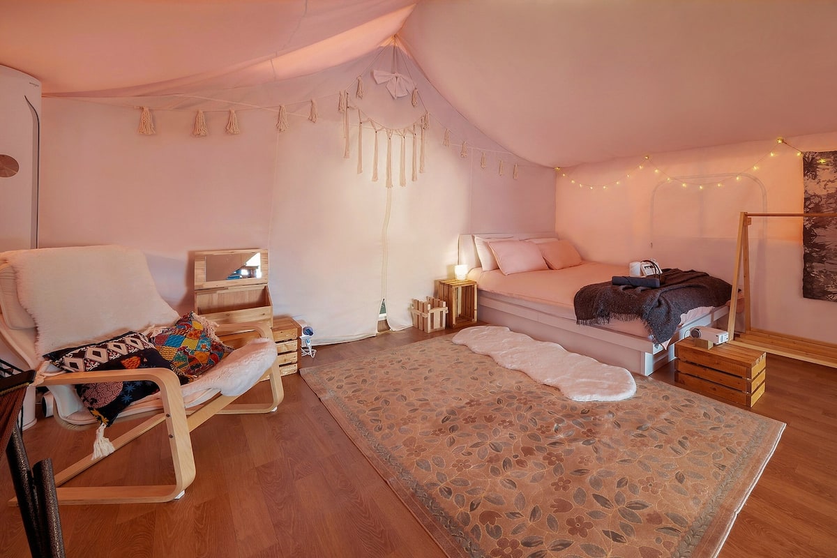 Un dormitorio acogedor con cama, una silla, un escritorio pequeño y un tapiz en la pared.