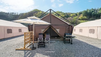 Un camping con dos tiendas de campaña, una con techo y otra sin, rodeado de grava.