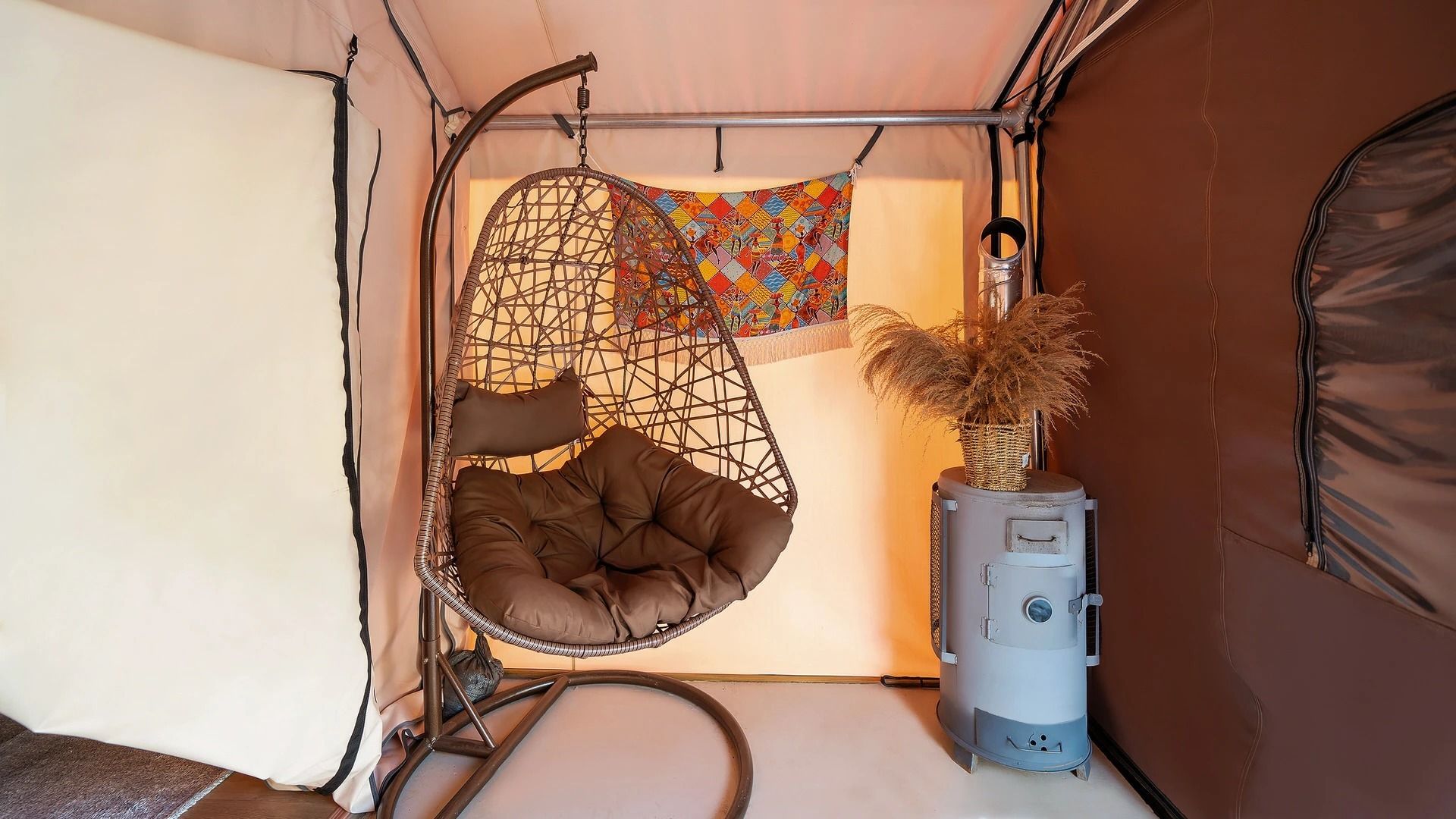 A cozy interior with a hanging chair, a decorative wall hanging, and a heater.