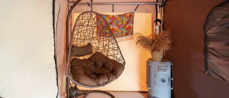 A cozy interior with a hanging chair, a decorative wall hanging, and a heater.