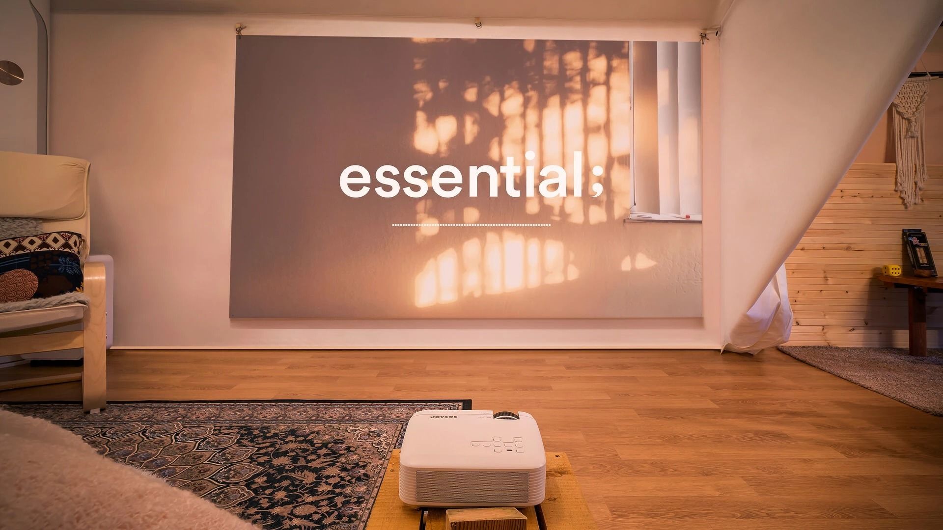 A room with a projector screen displaying the word 'essential,' a wooden floor, a patterned rug, a white ottoman, and a window with blinds.
