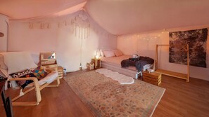 Ein gemütliches Schlafzimmer mit Bett, einem Sessel, einem kleinen Schreibtisch und Wandteppich.