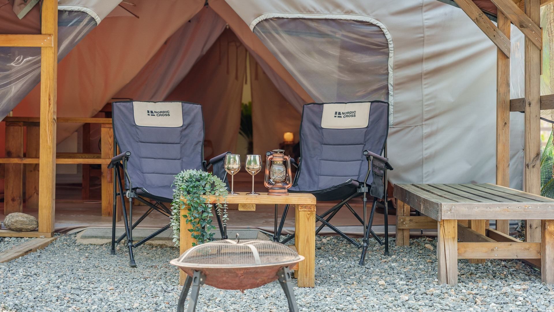 A tent with two chairs labeled 'Nordic Cross' and a table with two glasses and a lantern.