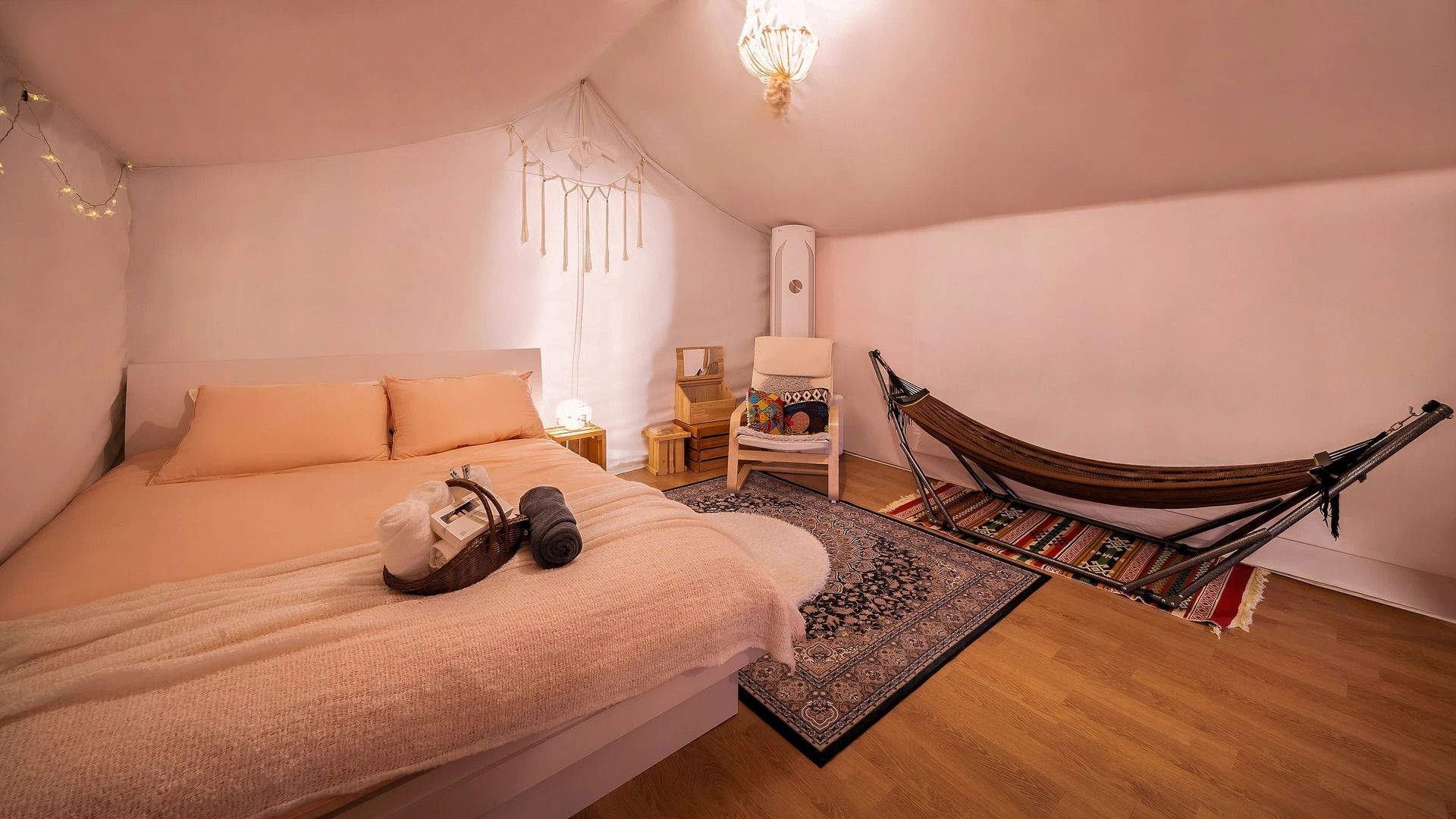 A bedroom with a bed, a hammock, a nightstand, and a wall-mounted lamp.