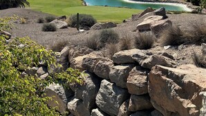 Ein Golfplatz mit Teich, umgeben von felsigem Gelände und spärlicher Vegetation.