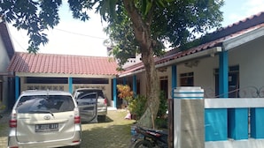 A building with a tiled roof and blue columns, a parked car, and a motorcycle. - Hotel O Lies Kostel Syariah (Kendal)