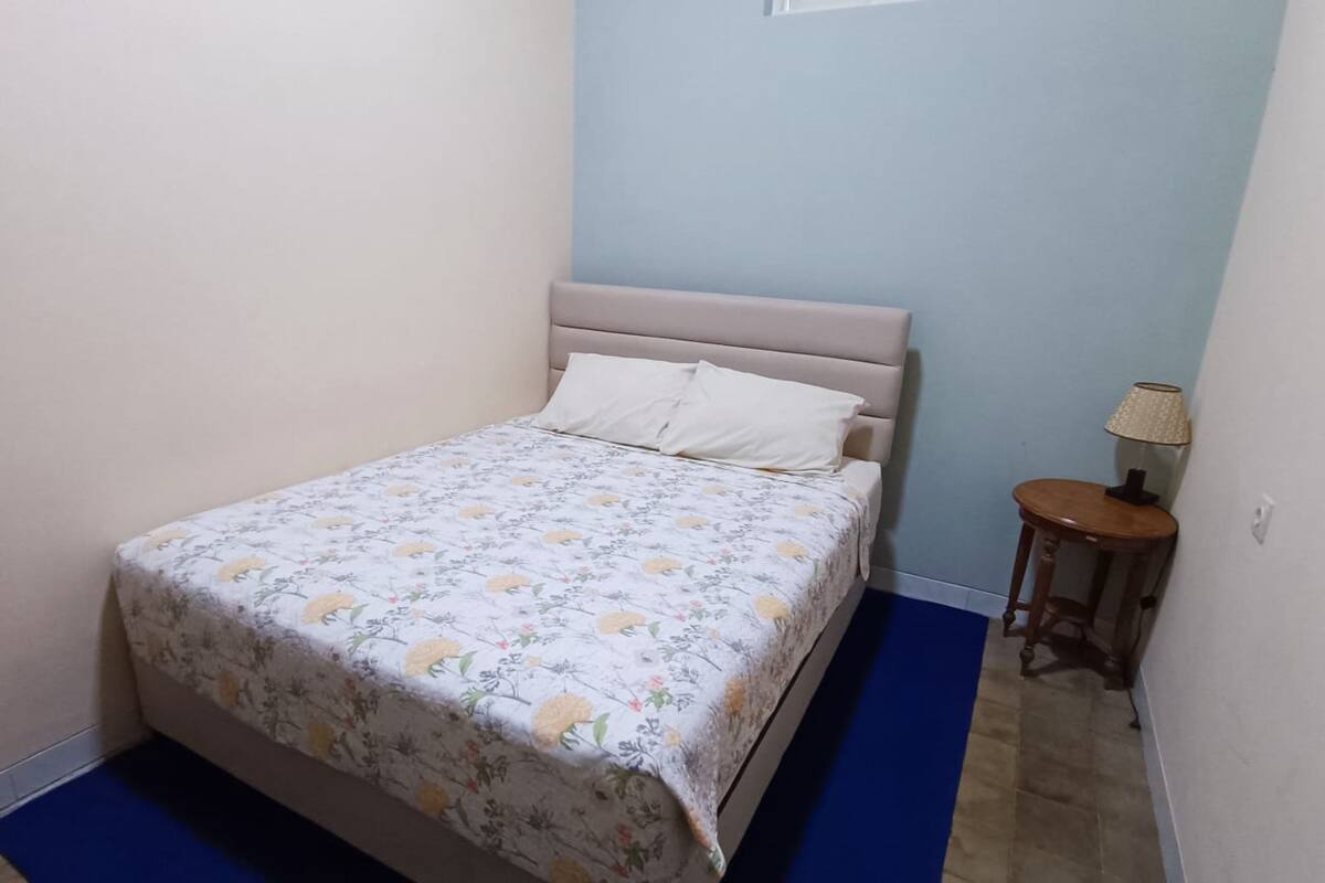 Un dormitorio pequeño con una cama, una mesita de noche y una lámpara.