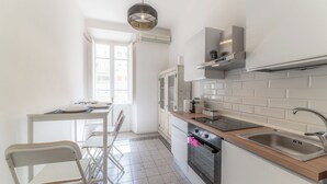 A modern kitchen with white cabinets, a stainless steel sink, and a built-in oven.