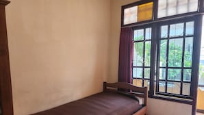 A single bed in a room with a window and a view of greenery outside. - Hotel O Regina Homestay Syariah (Surabaya)