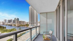 A balcony with a city view, a table with a plant, and a chair.