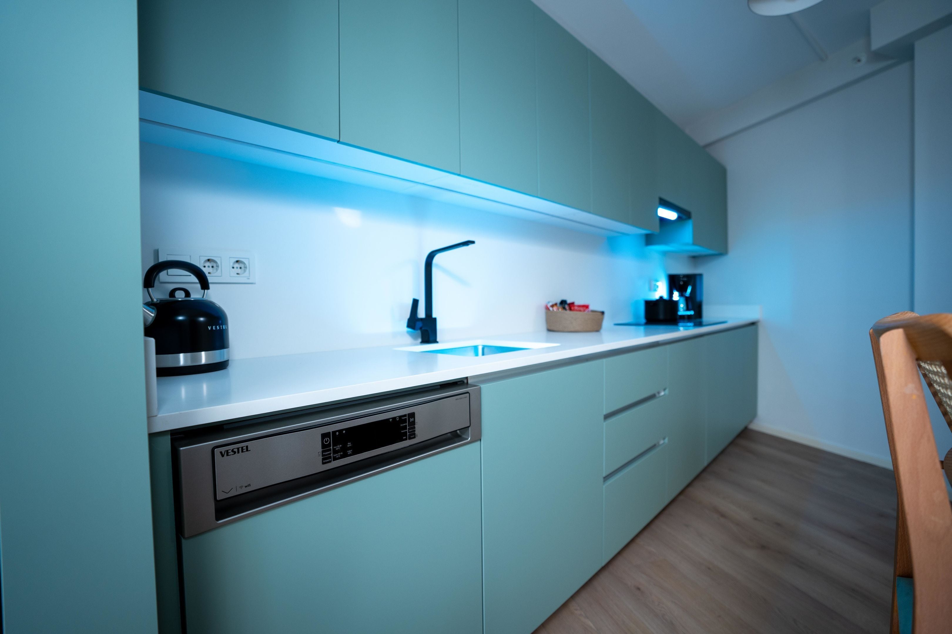 A modern kitchen with a dishwasher, a kettle, and a coffee maker.