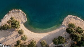 An aerial view of a beach with clear waters, rocky shorelines, and trees. - Aminess Younique Narrivi Hotel (Crikvenica)