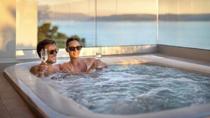 A couple in a hot tub with a view of a lake. - Aminess Younique Narrivi Hotel (Crikvenica)
