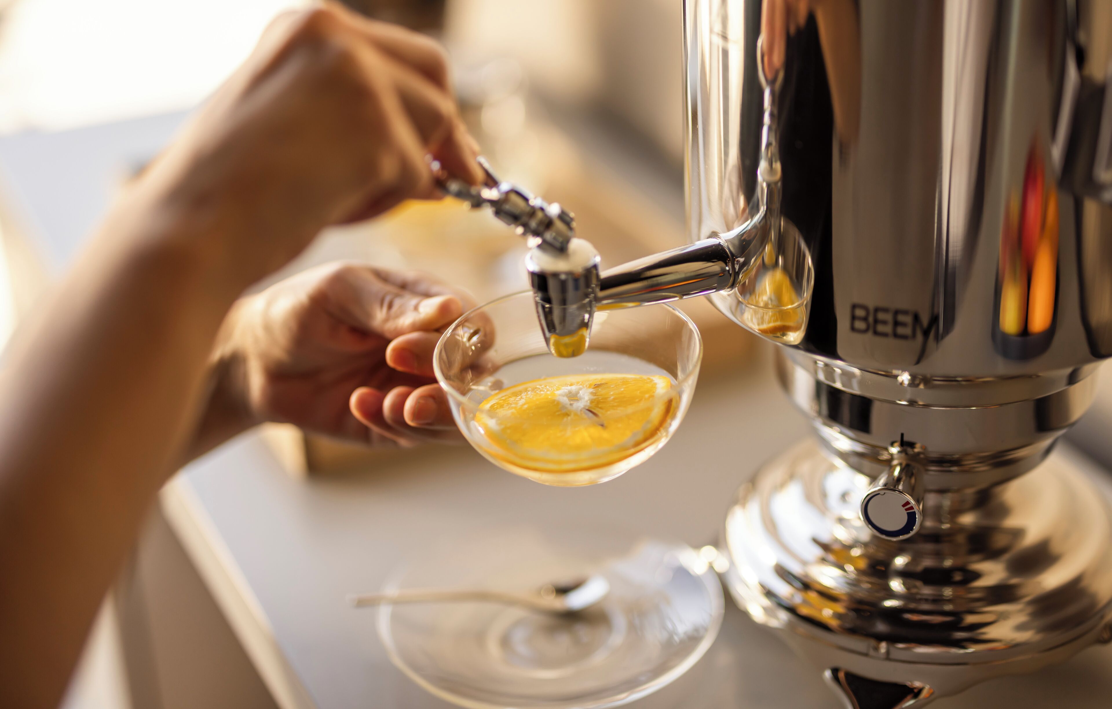 Una mano sosteniendo un vaso bajo un dispensador de bebidas, mientras se vierte un líquido transparente.