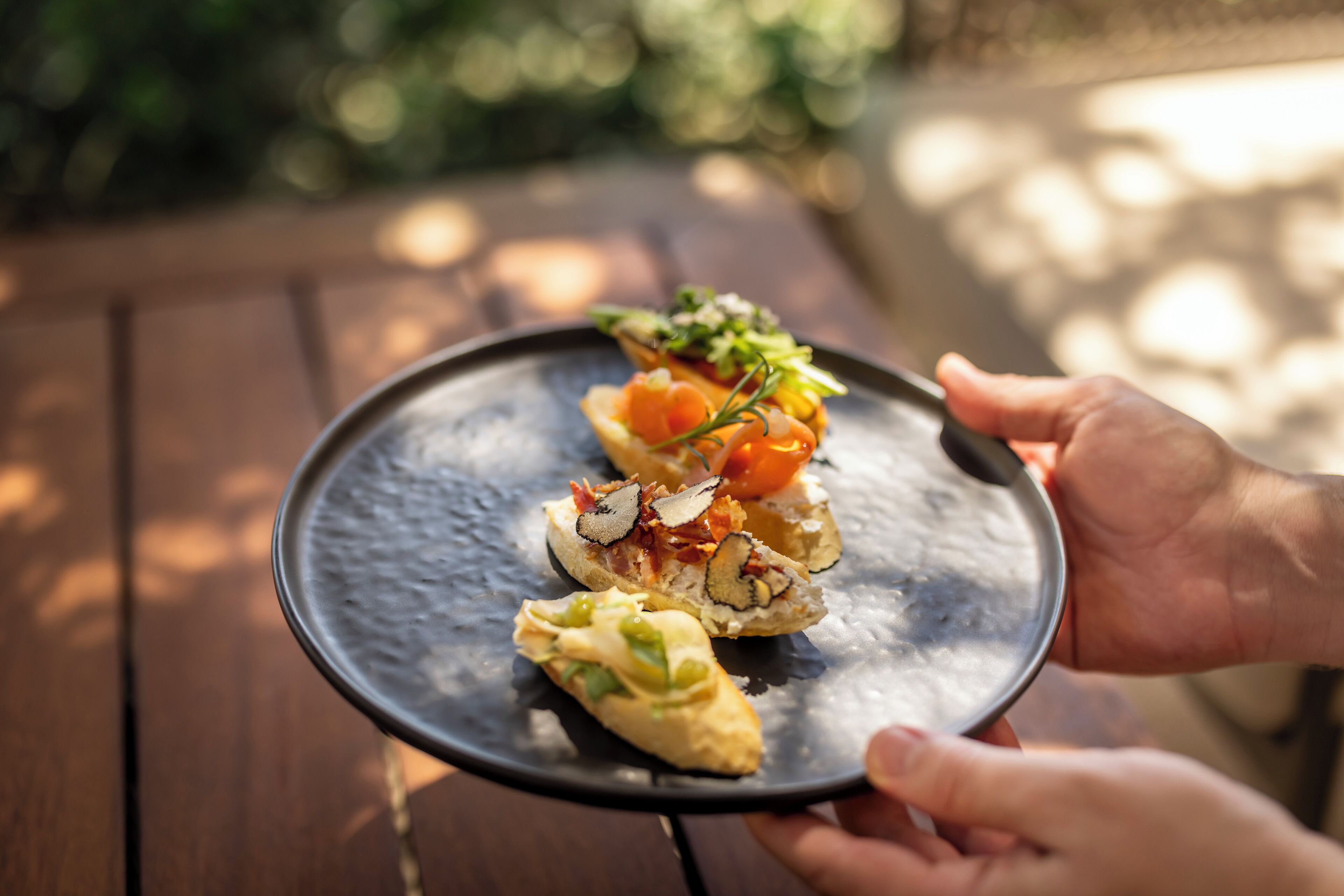 A person holding a plate with three appetizers.