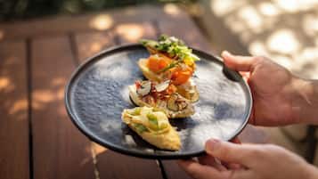 Una persona sosteniendo un plato con tres aperitivos.