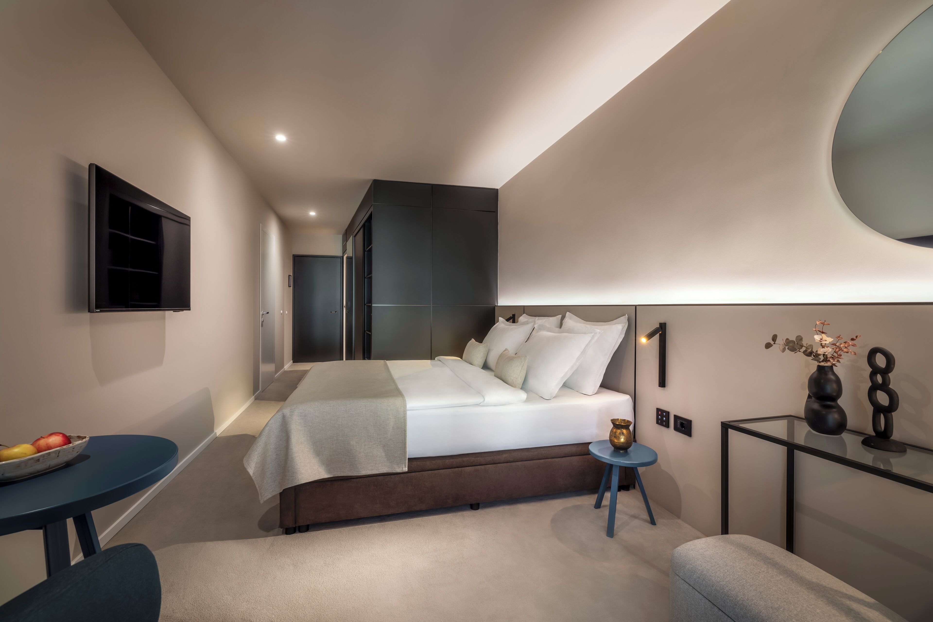 Een moderne slaapkamer met een bed, nachtkastje en een zithoekje.