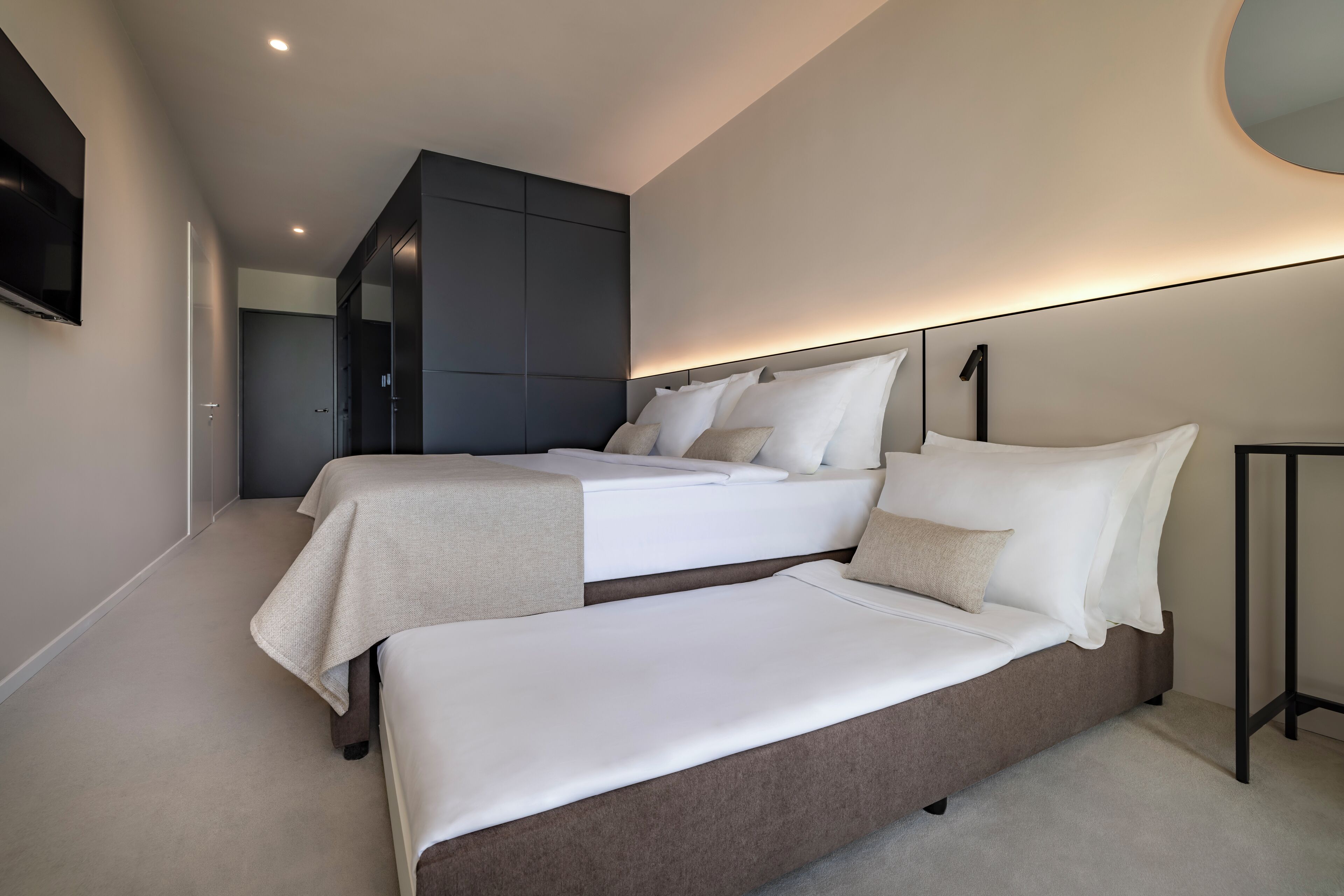 Un dormitorio moderno con dos camas, televisor y un diseño de techo original.