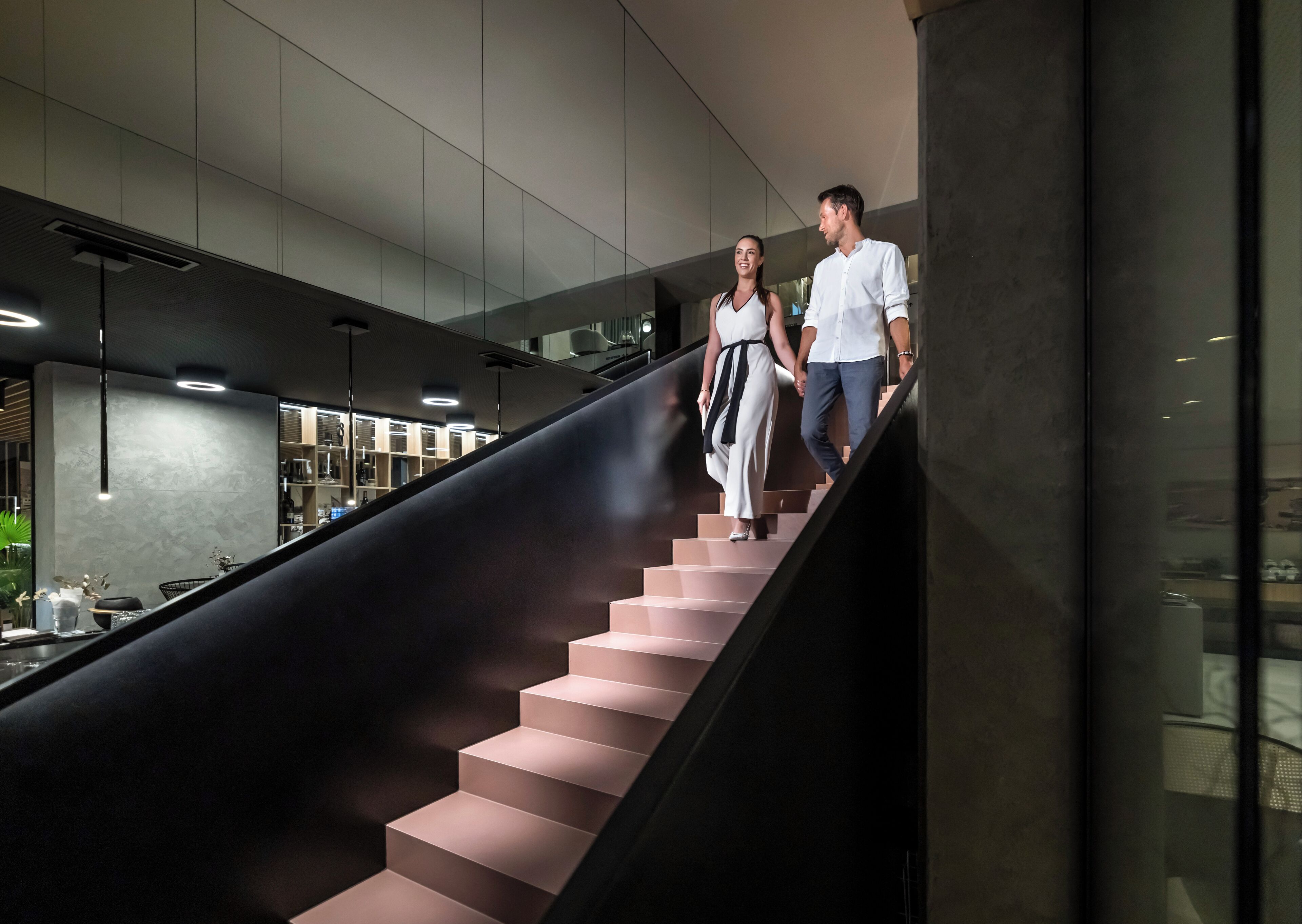 Una escalera moderna con un diseño elegante que conduce a un espacio bien iluminado con mobiliario contemporáneo.