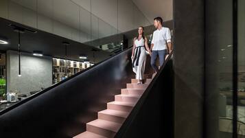 A modern staircase with a sleek design, leading to a well-lit area with contemporary furnishings.