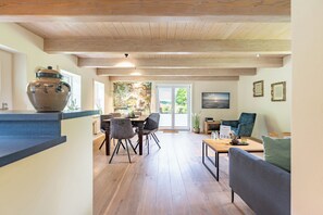 Une cuisine moderne avec une grande marmite, un coin repas avec des chaises, un canapé et un tableau accroché au mur.
