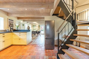 Une cuisine dotée d’un grand réfrigérateur, d’un escalier en bois et d’un coin repas avec des chaises.