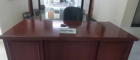 A reception desk with a nameplate reading "RECEPTIONIST" in a hotel lobby.