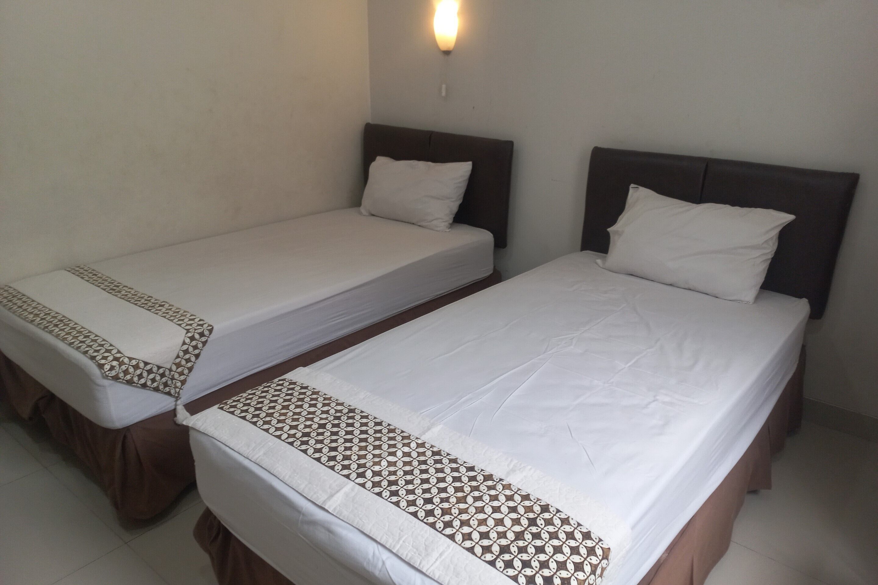 Two single beds with headboards, white bedding, and a patterned bed runner.
