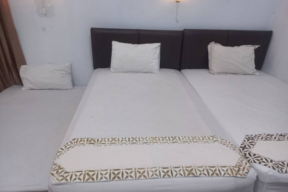 A hotel room with a large bed, two pillows, and a patterned bedspread.