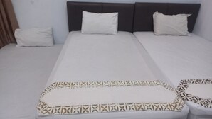 A hotel room with a large bed, two pillows, and a patterned bedspread.