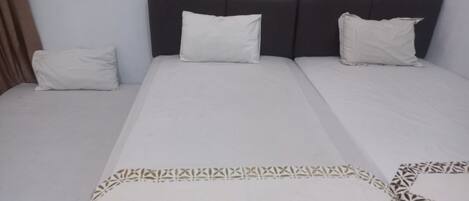 A hotel room with a large bed, two pillows, and a patterned bedspread.