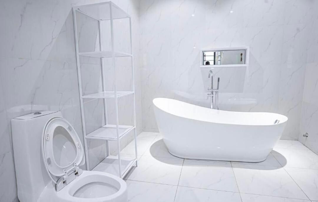 Ein modernes Badezimmer mit freistehender Toilette, einer Duschkabine aus Glas und einer freistehenden Badewanne.