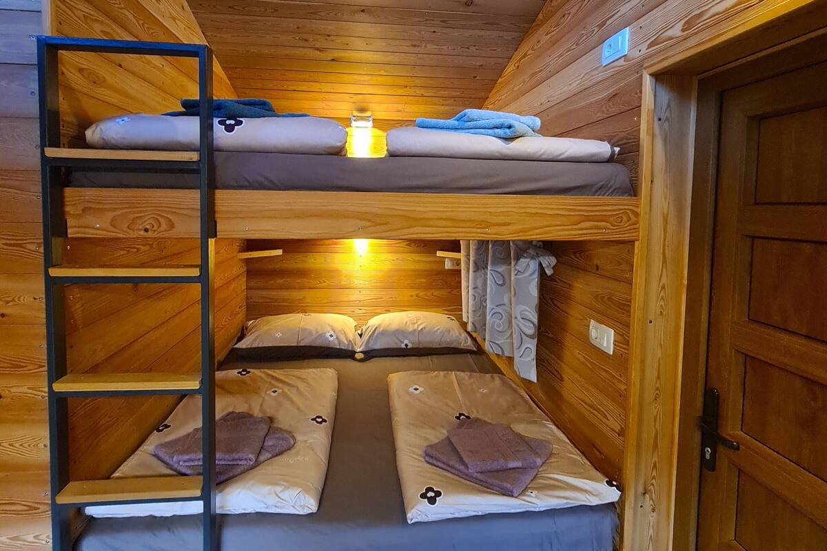 Une cabane en bois avec un lit superposé et une échelle.