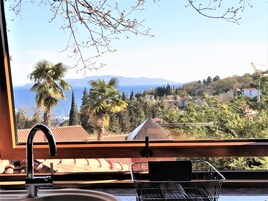 Una cocina con vista a un pueblo costero, un lavamanos y una estantería metálica.