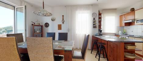A modern kitchen with a central island, wooden cabinets, and a dining area with wicker chairs.