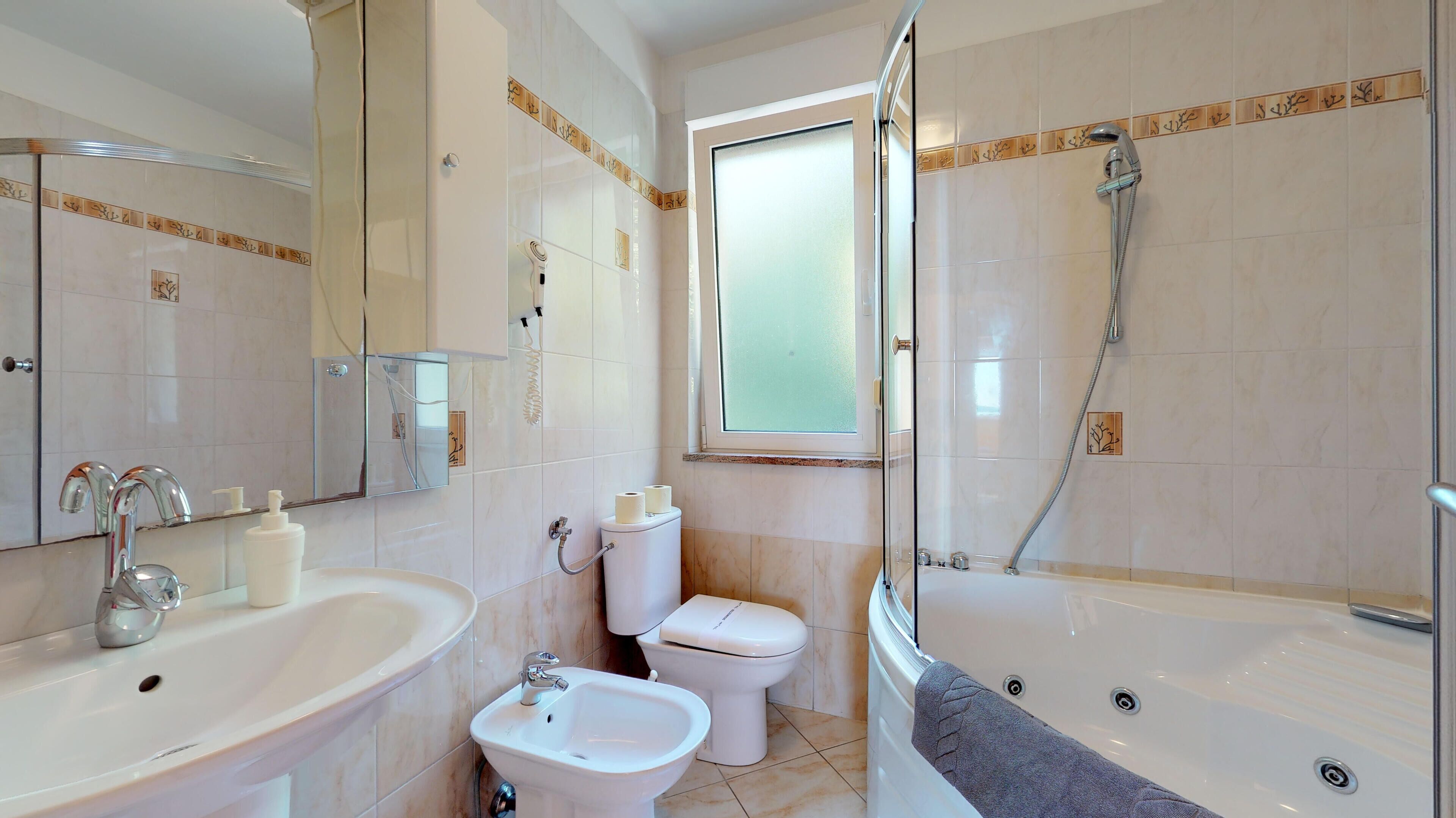 A modern bathroom with a sink, bidet, toilet, and a walk-in shower.