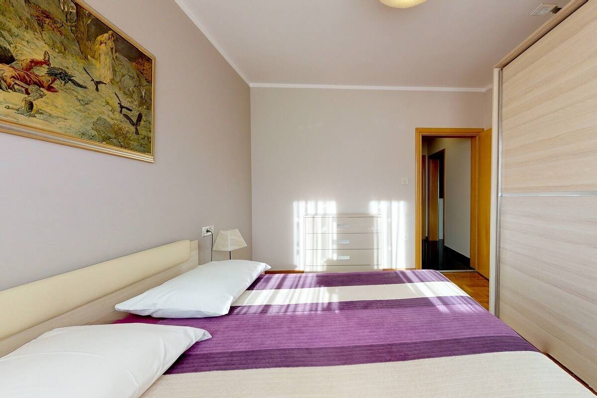 Une chambre à coucher avec un lit, une table de chevet, une lampe, une armoire et un tableau au mur.