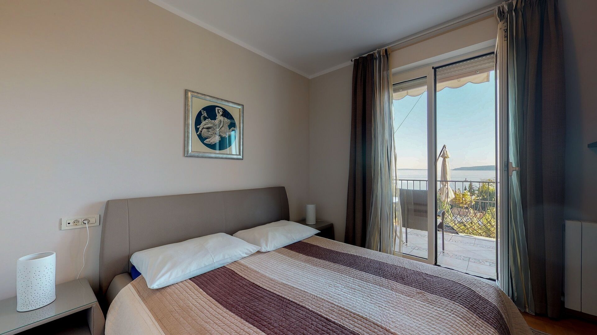 Une chambre d’hôtel avec un lit, un tableau au mur, une table de chevet et une vue sur l’extérieur grâce à une porte coulissante.