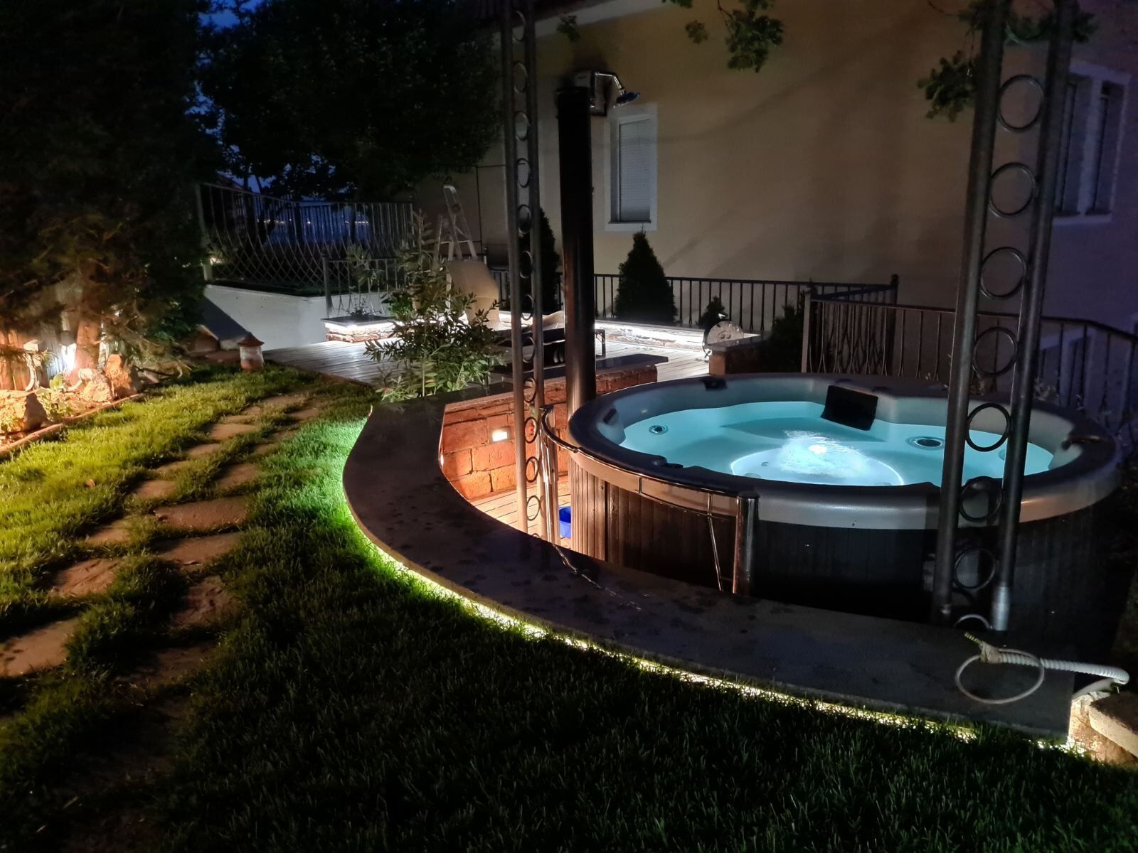 Ein Whirlpool in einem Garten mit einer Holterrasse und einer Backsteinmauer.