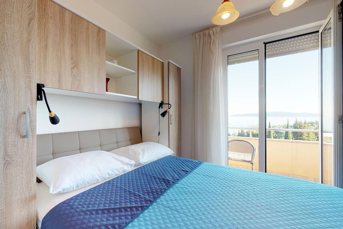 Une chambre à coucher avec un lit, deux lampes de chevet, une fenêtre donnant sur un beau paysage et un mur en bois.