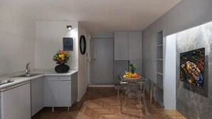 Cocina compacta con comedor, un lavamanos y una pequeña mesa con fruta y vasos.