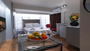Una habitación de hotel moderna con una cama, una mesa de vidrio con fruta, un escritorio y una silla.