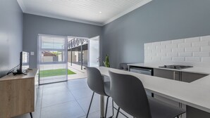 A modern kitchen with a white countertop, two grey chairs, and a built-in stove. - Inkantu Apartments & Suites (Cape Town)