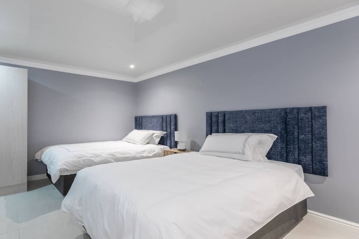A bedroom with two beds, a wardrobe, and a nightstand with a lamp.
