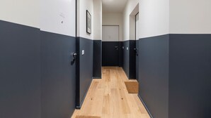 A narrow hallway with dark walls and wooden flooring, leading to a door at the end. - Easylife - Fantastic studio in Risorgimento area (Milano)