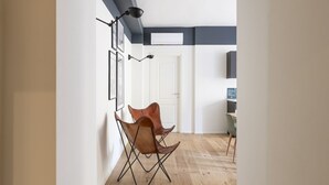 A modern living room with a wooden floor, a white door, and a brown leather chair. - Easylife - Fantastic studio in Risorgimento area (Milano)