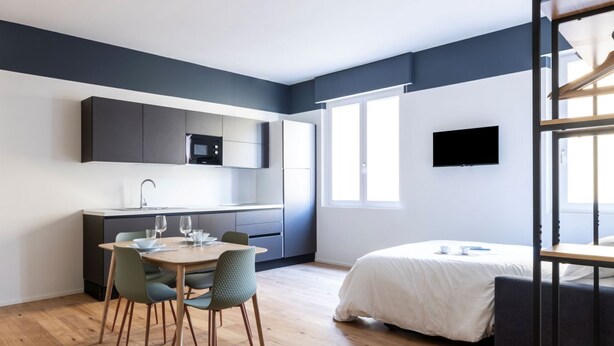 A modern hotel room with a dining area, kitchenette, and a large bed. - Easylife - Fantastic studio in Risorgimento area (Milano)