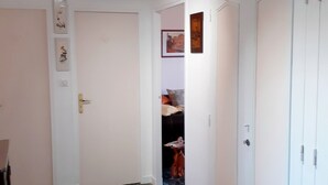A hallway with white walls, a marble floor, and doors leading to other rooms.