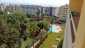 Ein Wohngebiet mit einem Schwimmbad, umgeben von viel Grün, neben einem Hochhaus mit Balkonen.